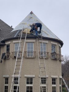  a man working on the roof of a home turret